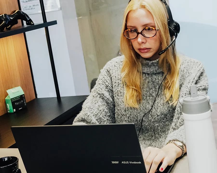 Profissional de headset trabalhando no notebook em uma estação do escritório da Hype Mídia