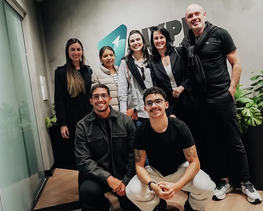Grupo reunido na recepção da Hype Mídia, diante da marca aplicada na parede